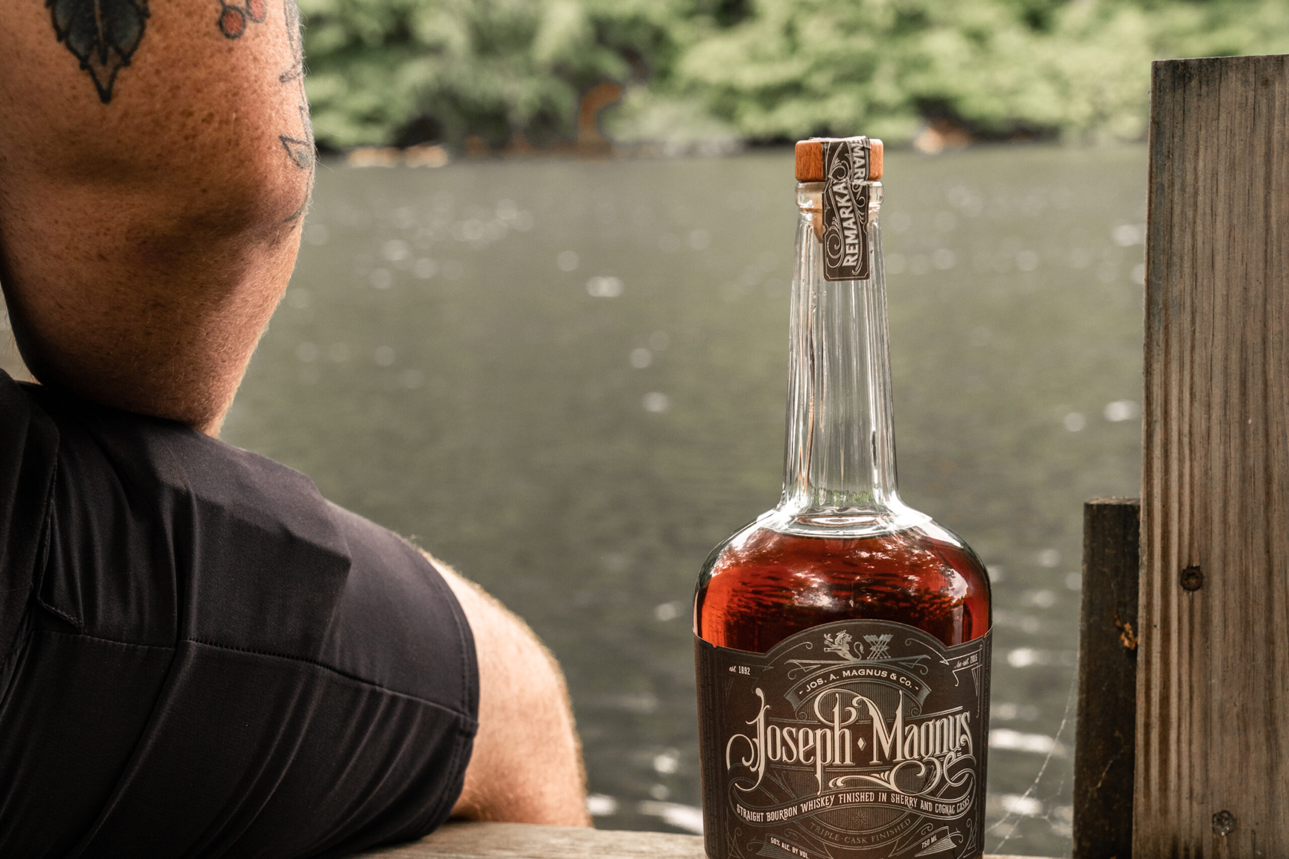 Father's Day Cocktails, man sitting on dock with whiskey bottle